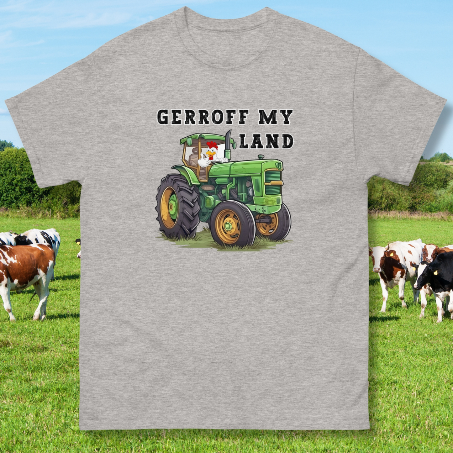 sport grey funny t-shirt with a green tractor with a cock in it with thumbs up that reads Gerroff My Land, laid flat with cows as a background