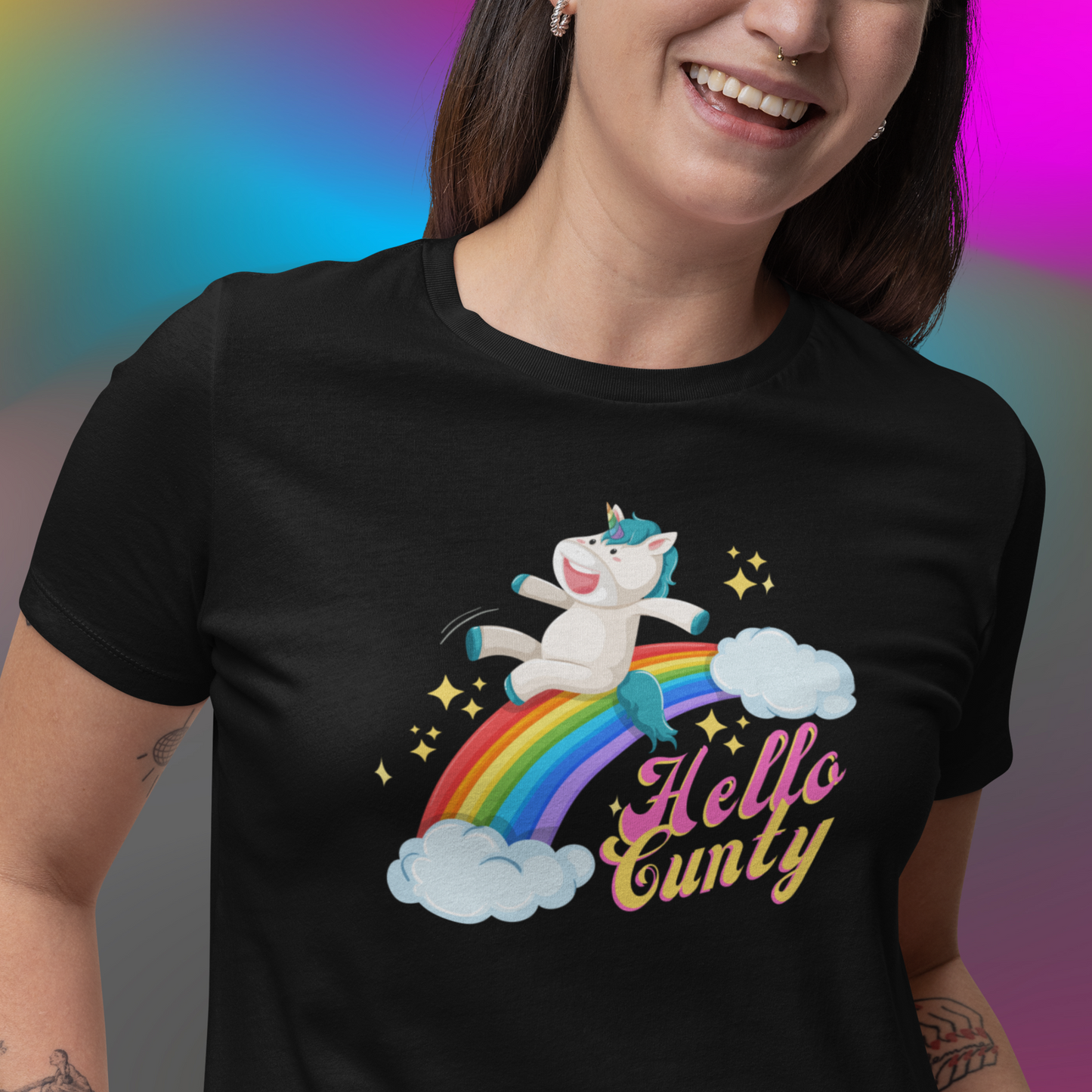 Laughing young woman wearing a Possibly offensive T-shirt that has a unicorn sliding down a rainbow on it with text that reads Hello Cunty, in black.