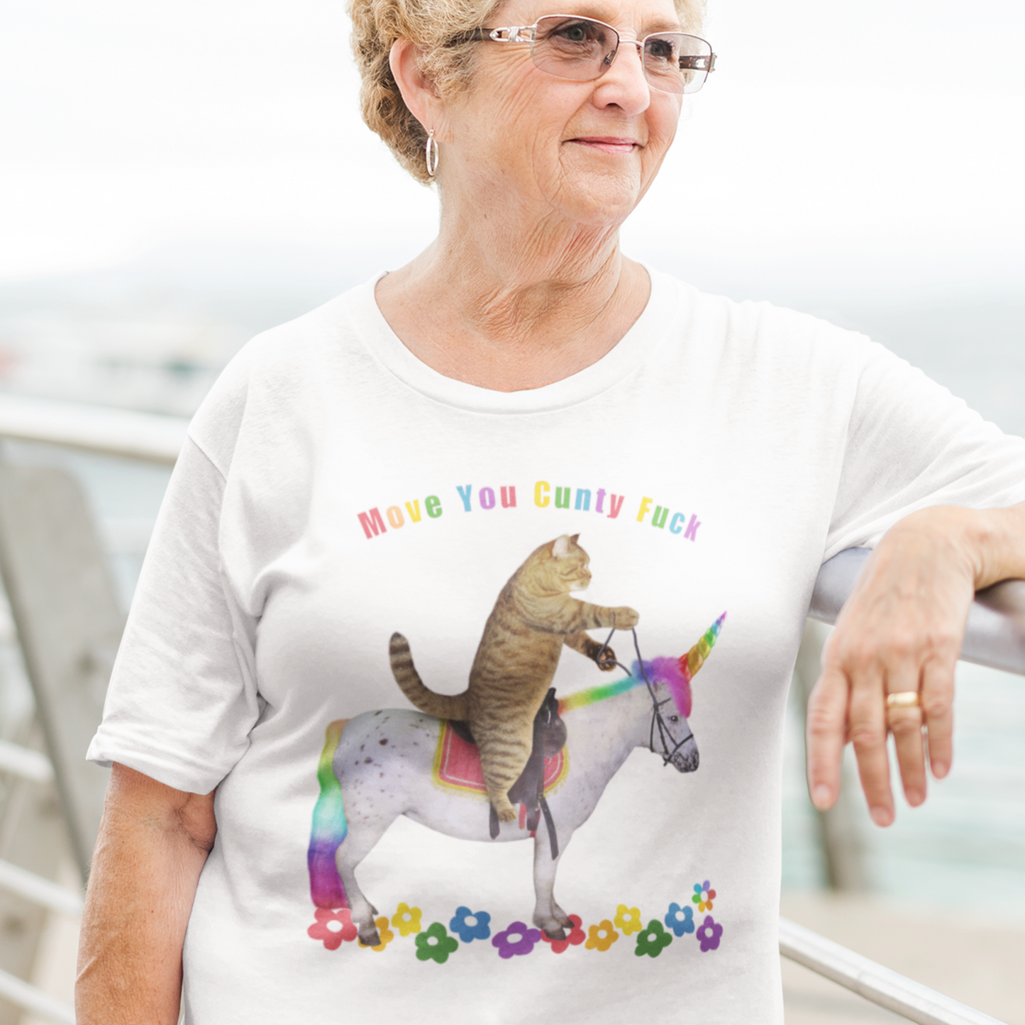 old lady wearing an Offensive cat riding a rainbow Unicorn T shirt which reads Move you Cunty F*ck, white