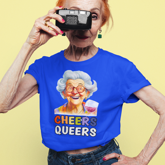 Quirky old lady holding a camera and wearing a royal blue Funny Cheers Queers! T-shirt with an illustration of an elderly lady laughing and raising a glass