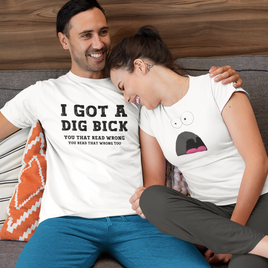 Young couple cuddled up and laughing hard. The man is wearing a I got a Dig Bick Optical Illusion T-shirt that reads 'I got a Dig Bick, You That Read Wrong, You read that wrong too'.