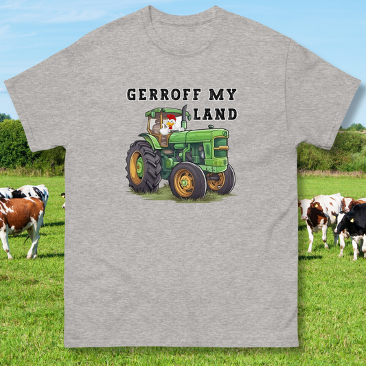 sport grey funny t-shirt with a green tractor with a cock in it with thumbs up that reads Gerroff My Land, laid flat with cows as a background