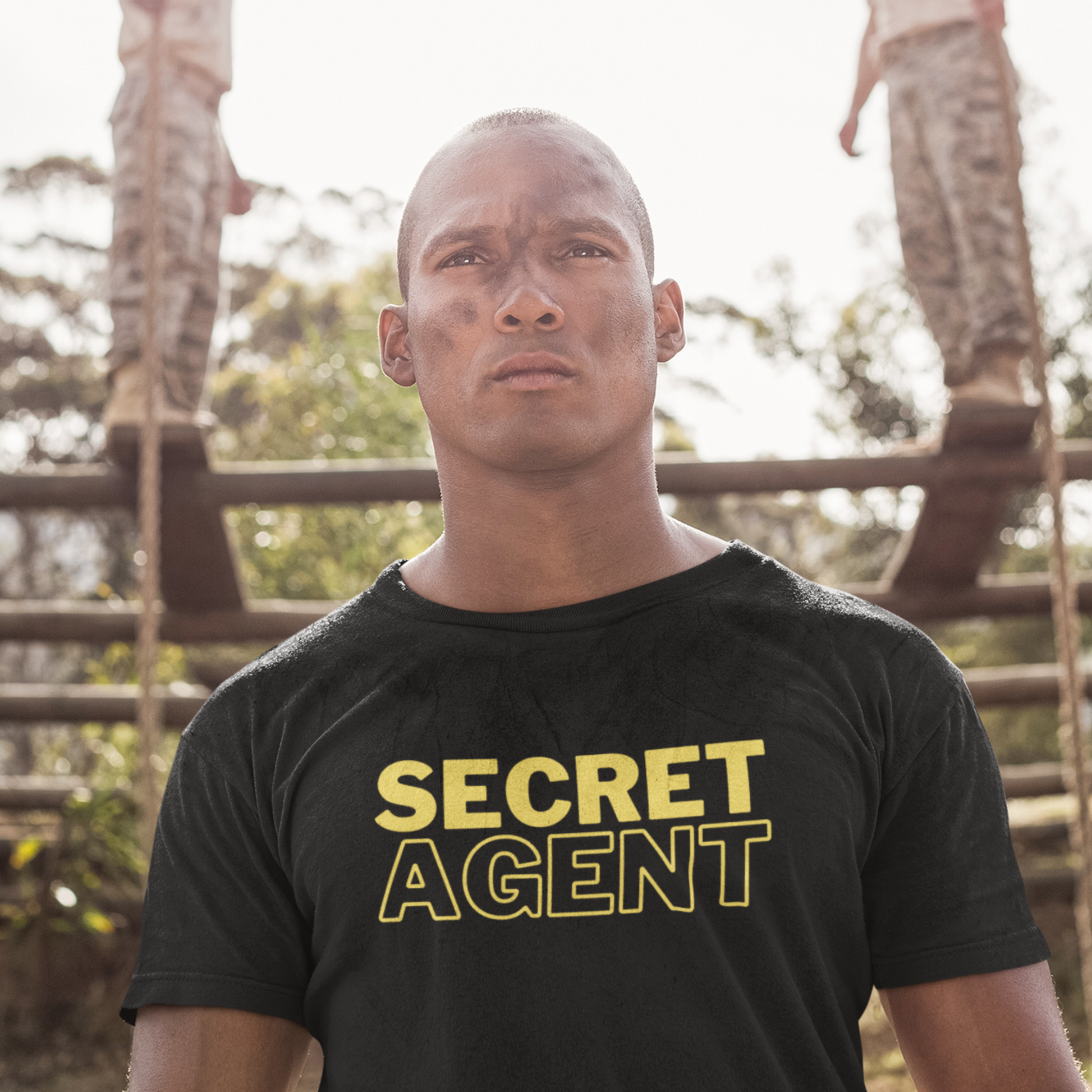 Scary military type man wearing a Black unisex T-shirt that reads SECRET AGENT in yellow text