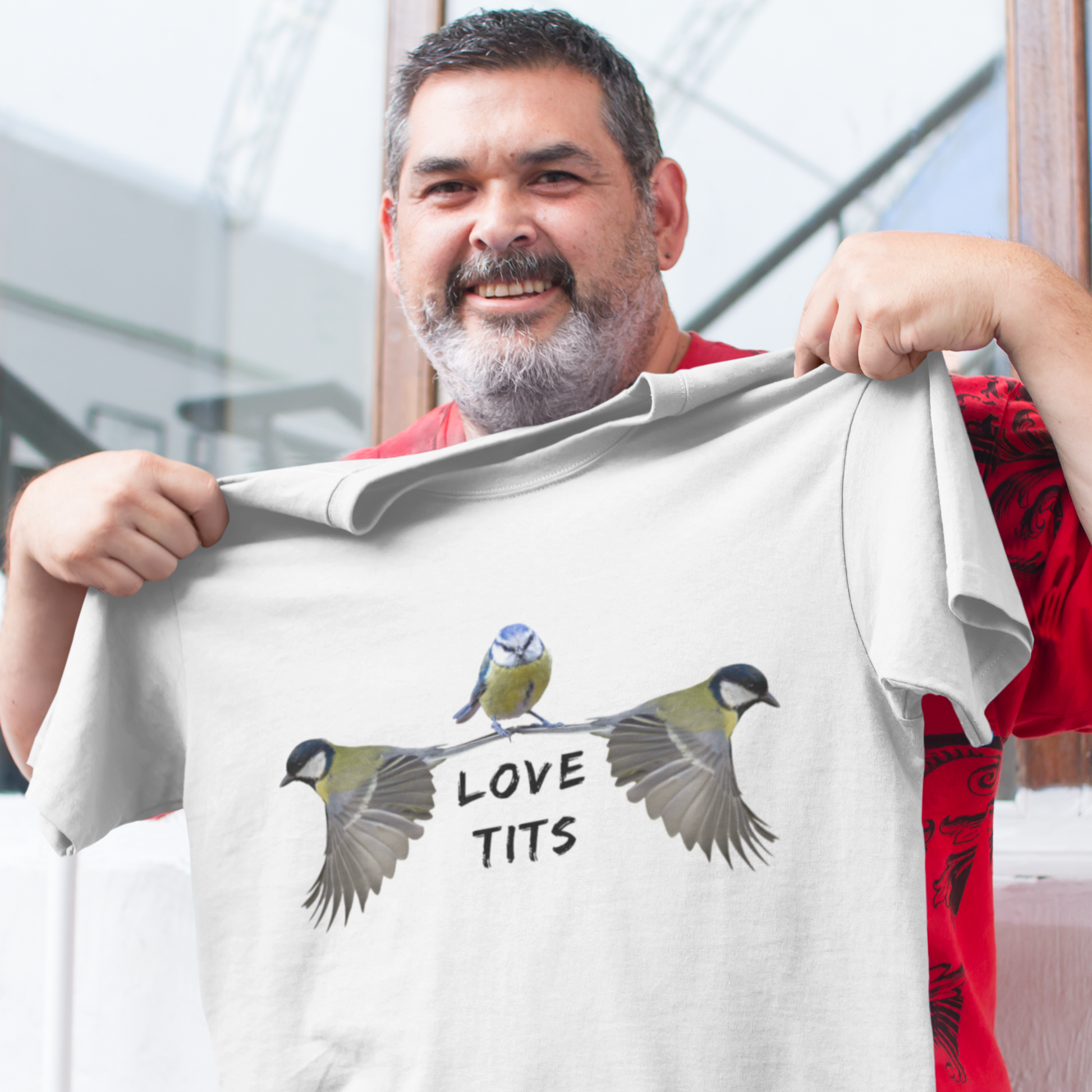 Man holding up a funny white Tshirt that reads Love Tits and has wild birds on