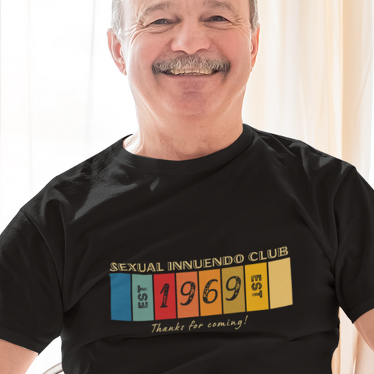 Older man laughing and wearing a Funny retro T-shirt that reads Sexual Innuendo Club, EST 1969, Thanks for coming! in black.