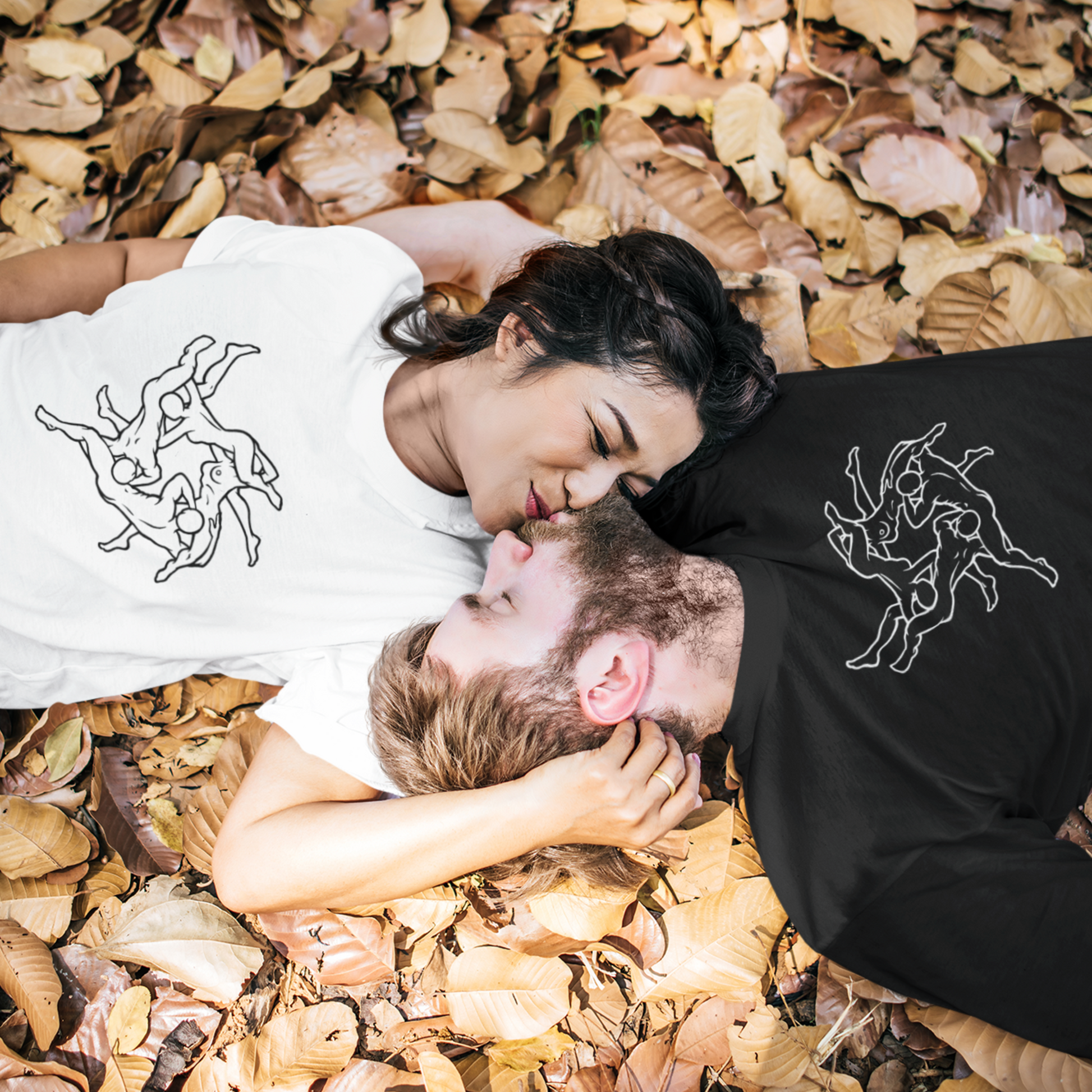 young couple laying in autumn leaves, head to head, wearing a T-shirt with four adults having an orgy outline graphic, in black and in white.