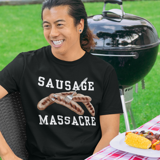 Young man at a BBQ wearing a black funny sausage massacre T-shirt with a fork through a shocked sausage.