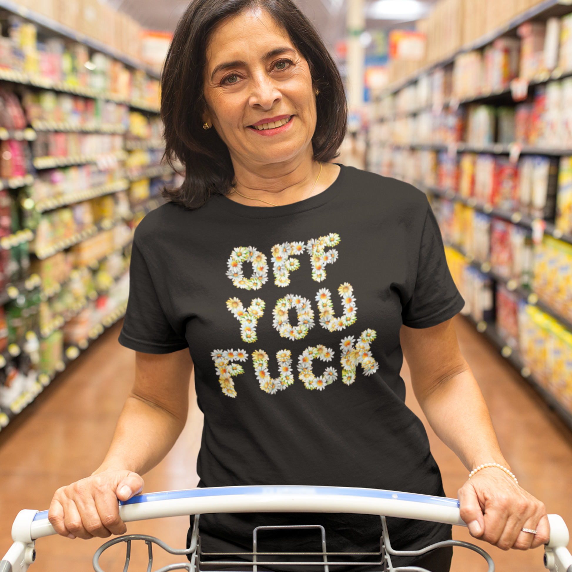 Middle aged woman pushing a supermarket trolley wearing an offensive Off You Fuck written in Daisies T-shirt in black