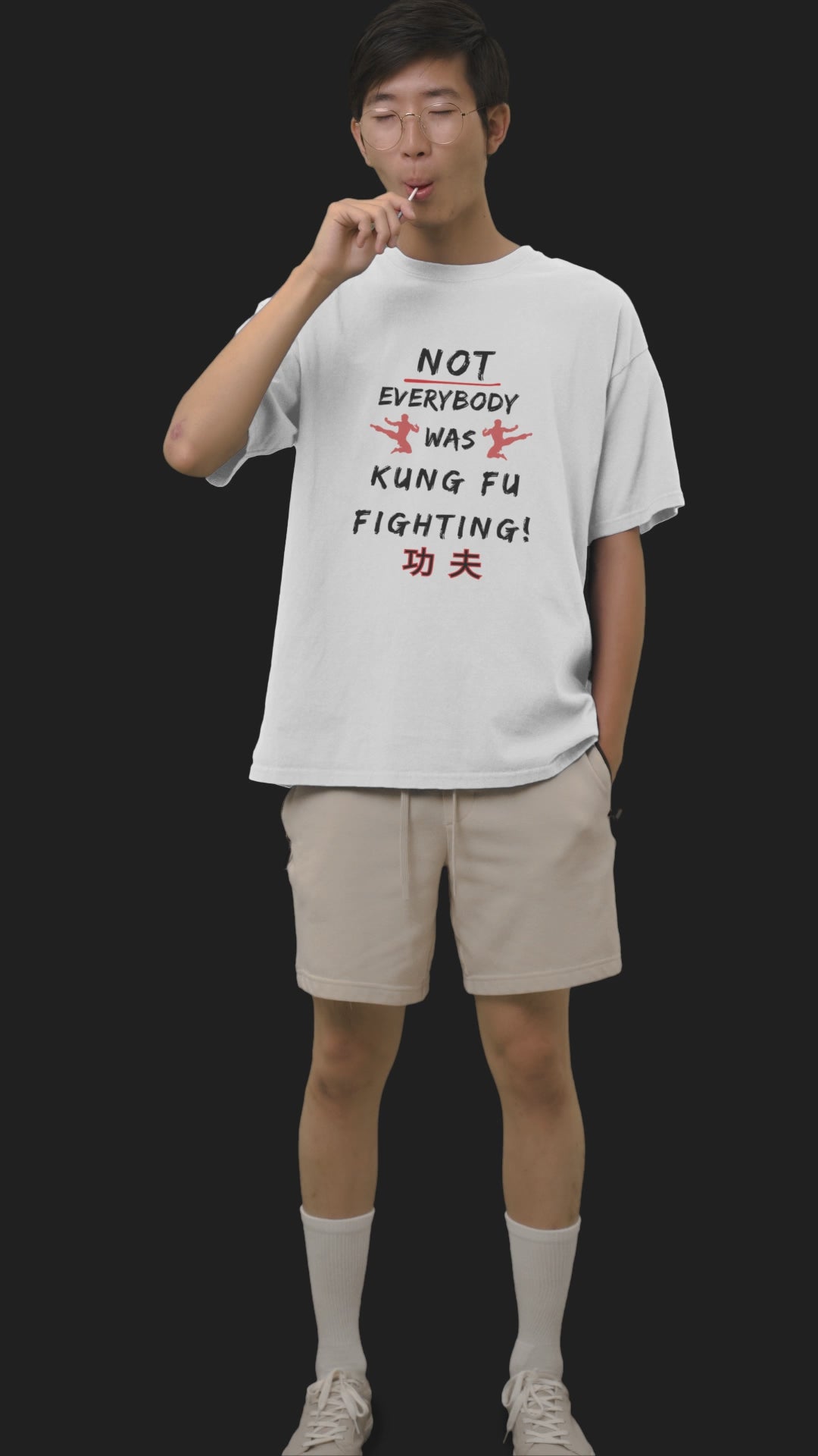 Young Asian man standing whilst drinking and eating wearing a white T-shirt that reads Not Everybody Was Kung Fu Fighting