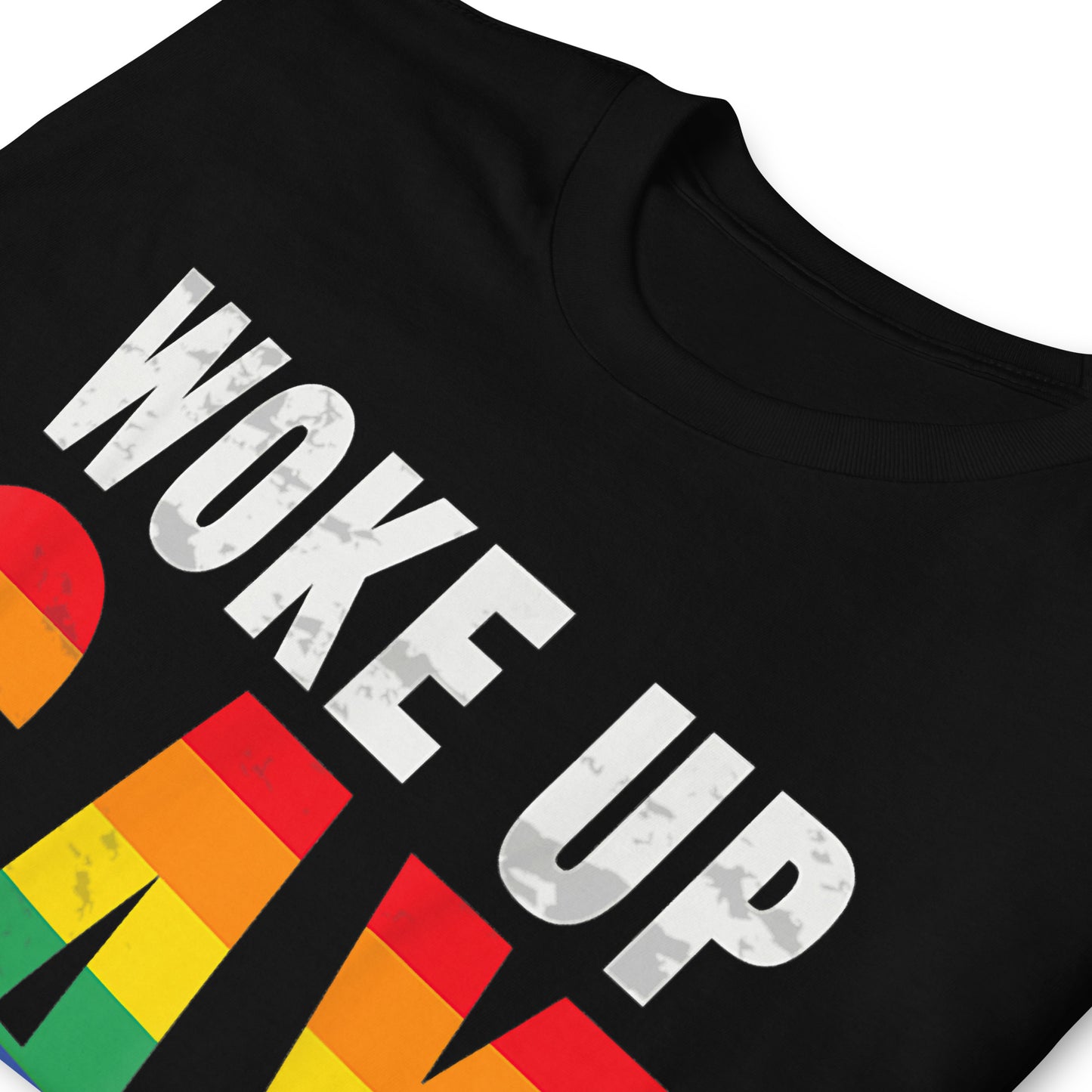 Folded black t-shirt that reads Woke Up Gay Again in pride colours