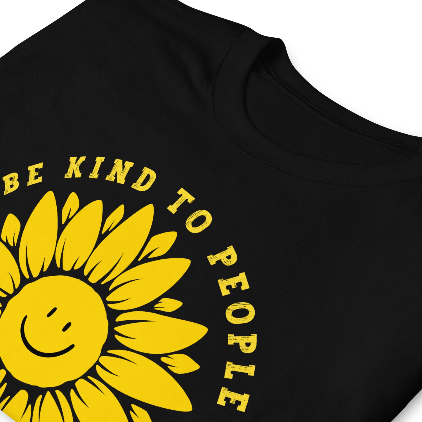 Funny T-shirt with a smiling sunflower design and yellow text that reads, Be Kind To people, Just Kidding, Hail Satan! Black, folded.