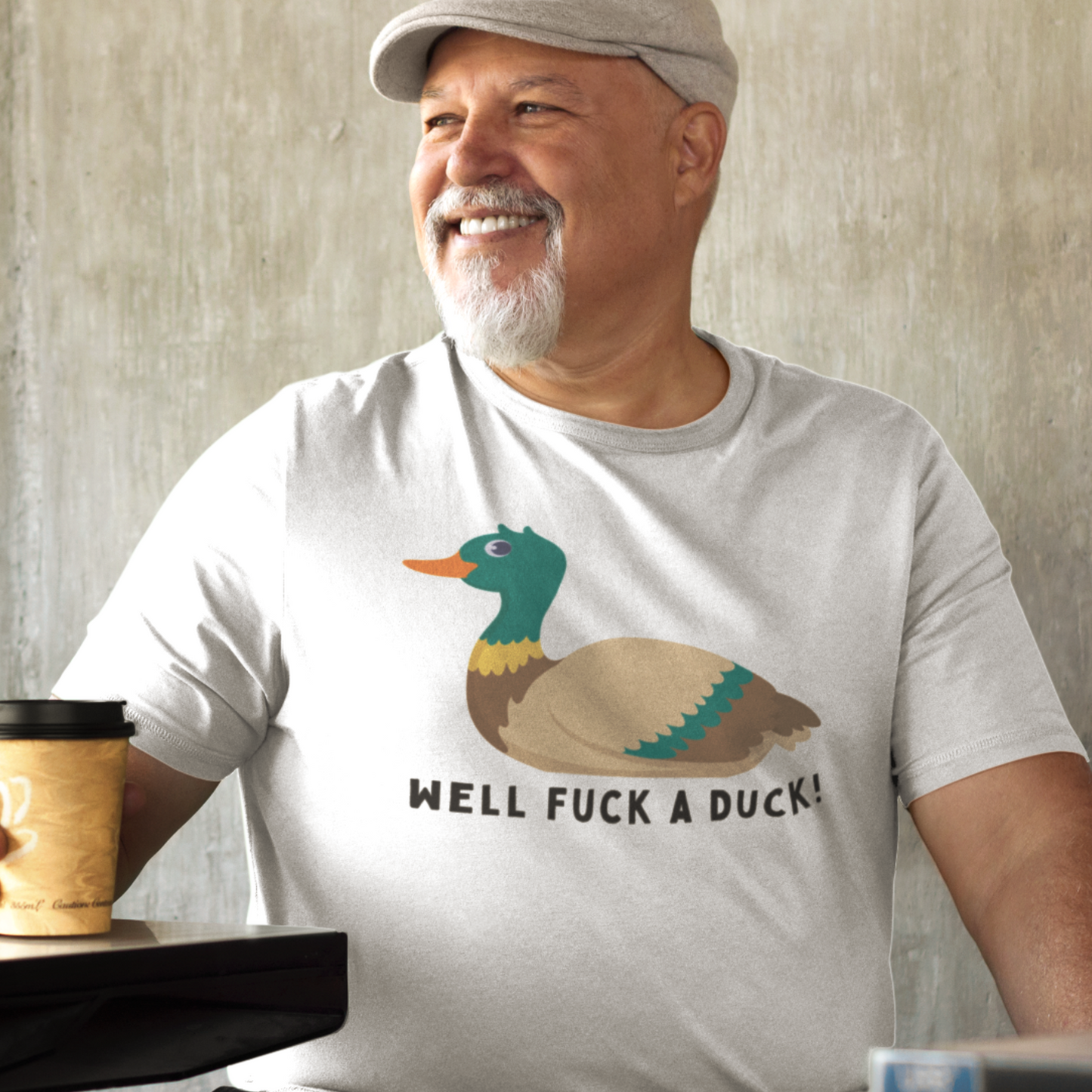 Fat happy man wearing a white Well Fuck a Duck T-shirt in a coffee shop.